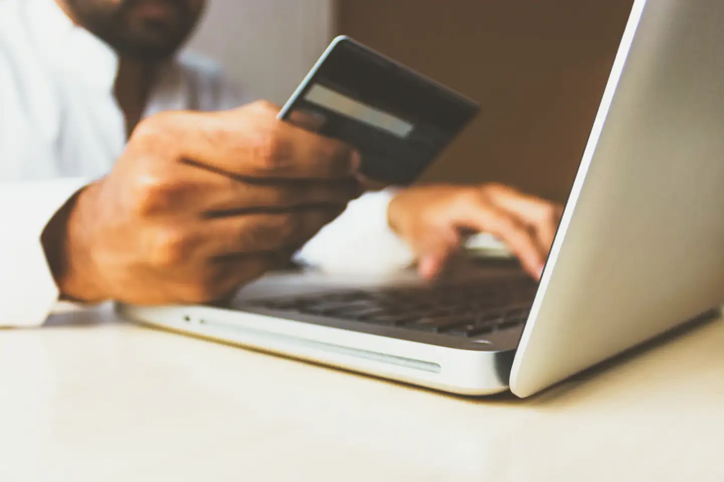Person paying online with a card and laptop