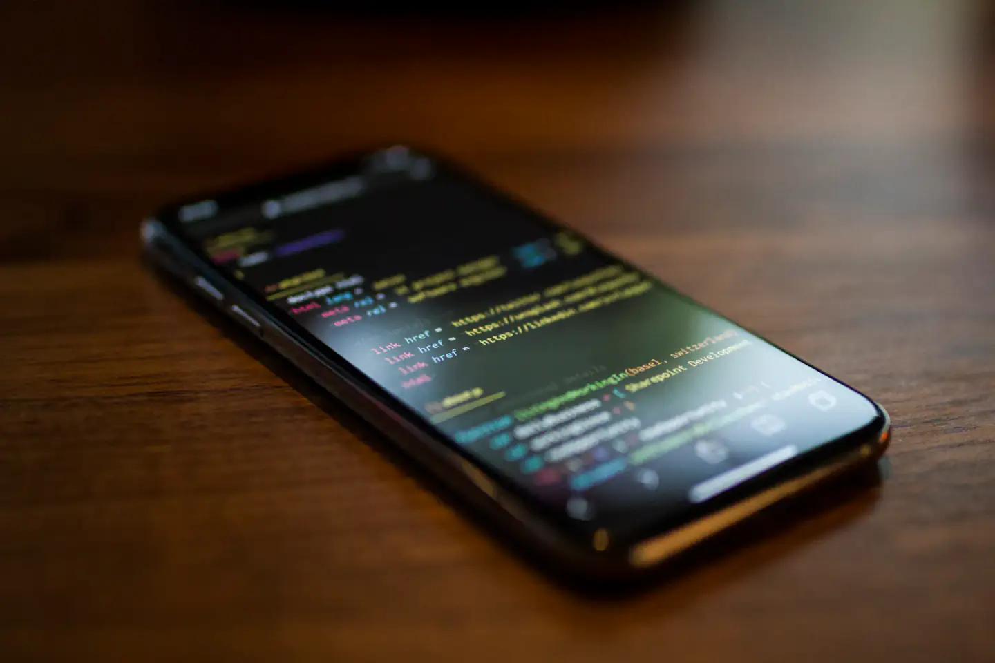 Smartphone displaying code on a wooden desk